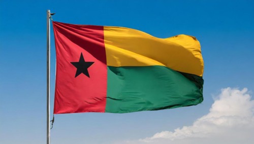 The flag of Guinea-Bissau, fluttering in the wind, isolated, against the blue sky