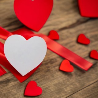 Rustic wooden table with many red hearts. The main heart is white and customizable for a