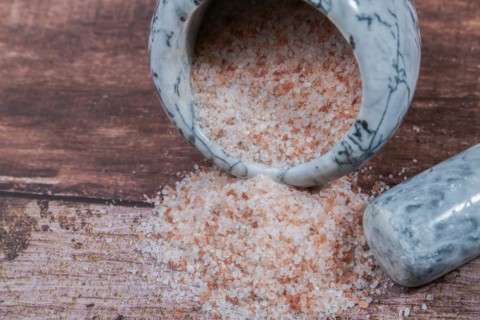 Himalayan pink salt in a ceramic mortar on a wooden table with a copy space
