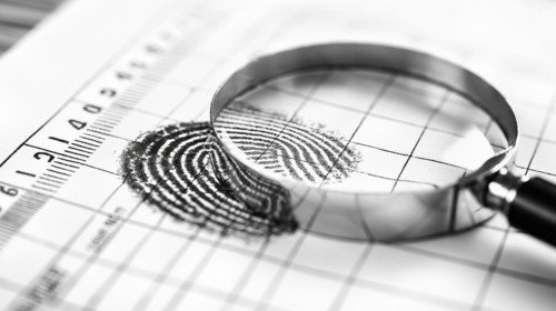 Magnifying glass resting on a fingerprint on paper. generative AI, AI generated