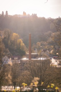 Industrial chimney rises into a sky at sunset with trees, spring, Calw, Black Forest, Germany,