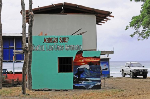 San Juan del Sur, Nicaragua, Colourful surf school with mural on the beach and parked car, Central
