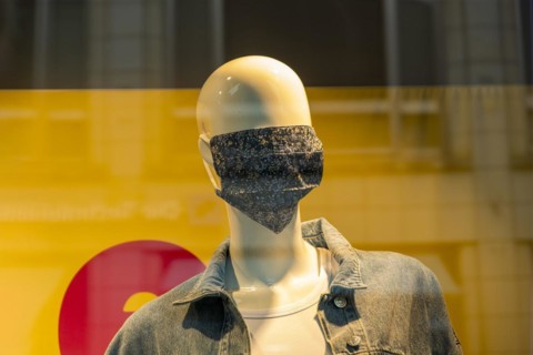 Mannequin with a corona mask on its face in a shop window of a fashion shop in the city centre of