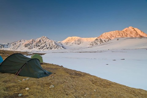 Icy tents in expedition camp at sunrise over the mountain peaks in the snow-covered Tavan Bogd