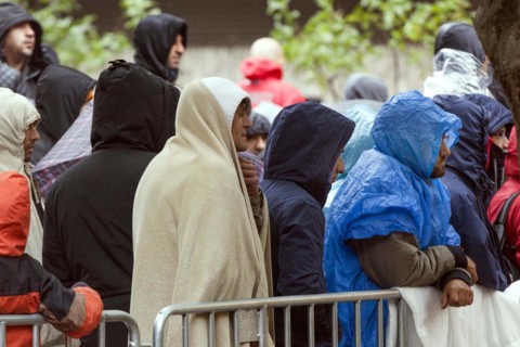 Syrian refugees wait for their registration in cold and wet weather at the Berlin State Office for