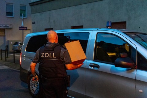 Customs officer at work, carrying cardboard to the official vehicle at dusk, The Cologne police led