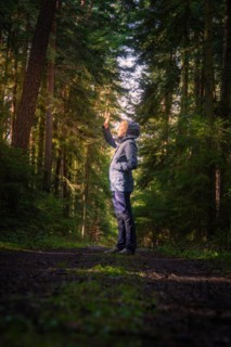 A hiker raises his hand in greeting or to block the sunlight in the dense forest, Calw, Black