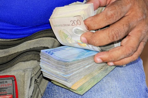 Leon, Nicaragua, hands counting Honduran Lempira banknotes in front of an open bag, Central