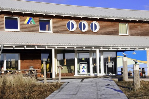 Youth hostel, Beach at Dikjen Deel, Colourful building with various signs and clear sky above,