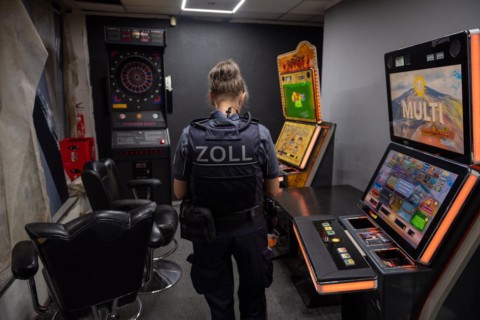 Customs officer looks at slot machines and surveillance equipment in a dark room, The Cologne