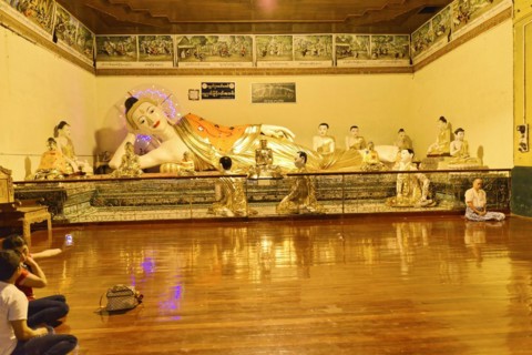 Shwedagon Pagoda, Yangon, Myanmar, Asia, Reclining Buddha statue in a temple, surrounded by praying