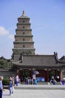 Traditional Chinese pagoda under a clear blue sky with visitors in front of it, Chongqing,