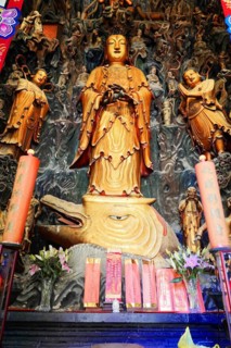 Jade Buddha Temple, Shanghai, Large gold-coloured statue in Asian style with red candles and flower