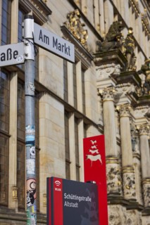 Street sign Am Markt and signpost to Schuettingstrasse and Old Town with red Bremen Town Musicians