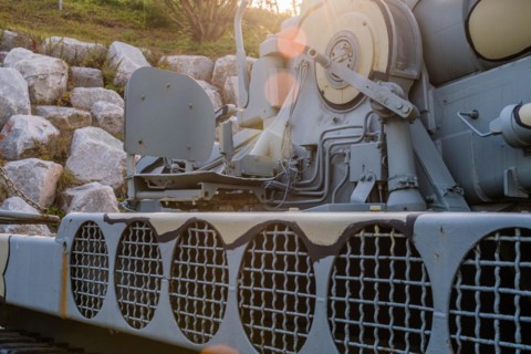 Side view of camouflaged army tank with vents above track and closeup view of chair on rear portion