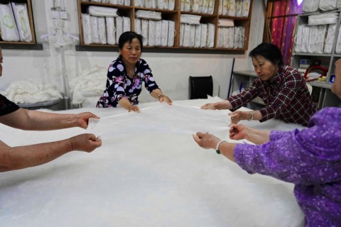 Silk factory Shanghai, Several workers stretching a large length of fabric together, Shanghai,