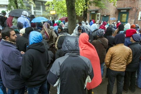 Syrian refugees wait for their registration in cold and wet weather at the Berlin State Office for