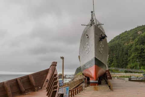 The bow of a wooden boat and exterior of South Korean battleship on display in Unification Park in