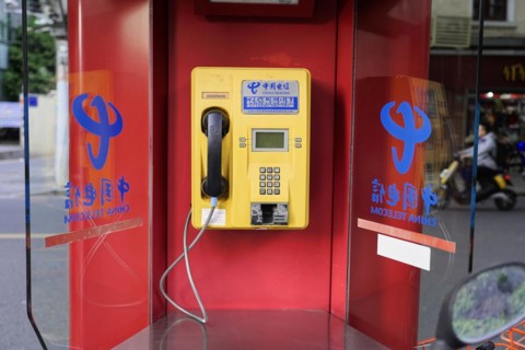 Shanghai, China, Asia, Red public telephone box with Chinese characters and reflections in glass,