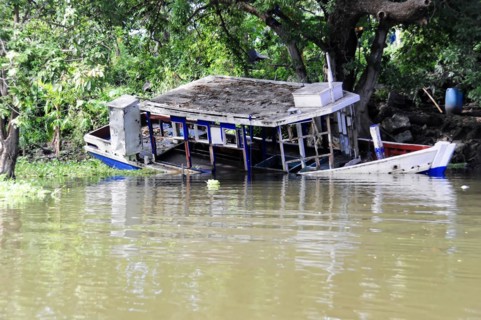 Granada, Nicaragua, Half-sunken boat at Lake Nicaragua surrounded by lush greenery, Central