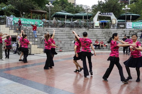 A group of people in uniform costumes dancing together in a public square, Chongqing, Chongqing,