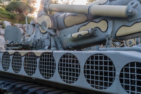 Closeup of camouflaged army tank with side view of vents above track and chair on rear portion of