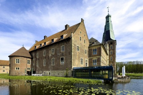 View over wide moat to historic moated castle from Renaissance Schloss Raesfeld, water lilies in