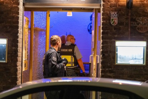 A customs officer enters an illuminated business premises in the evening hours, The Cologne police