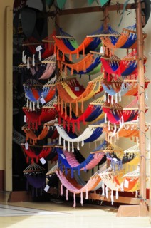Granada, Nicaragua, Colourful hammocks displayed in front of a shop, hung on a large wooden frame,