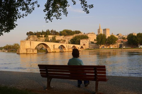 Woman on a park bench on the banks of the Rhone, Pont Saint Benezet bridge, Papal Palace and