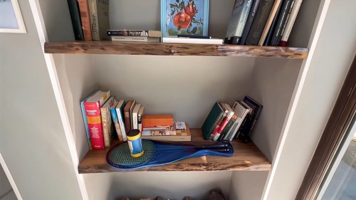 Bookshelf with books and cleaning equipment in a home library