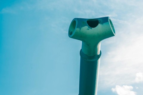 Closeup of muzzle brake on end barrel of tank gun with signs of wear and usage against a beautiful