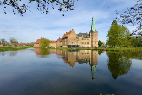 View over moat to historic moated castle from Renaissance Raesfeld Castle reflected in moat in