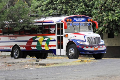 On the road near Rivas, Ometepe Island, Nicaragua, Parked colourful city bus surrounded by trees on