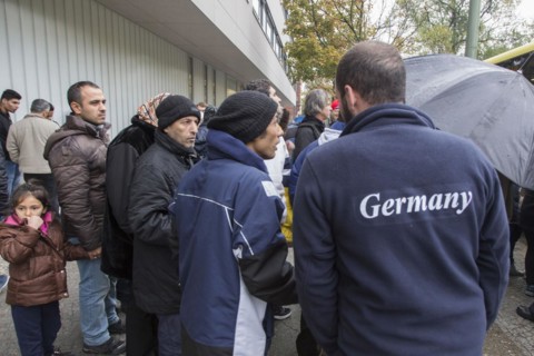Syrian refugees wait for their registration in cold and wet weather at the Berlin State Office for