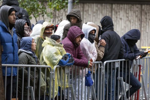 Syrian refugees wait for their registration in cold and wet weather at the Berlin State Office for