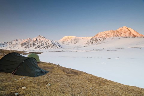 Icy tents in expedition camp at sunrise over the mountain peaks in the snow-covered Tavan Bogd