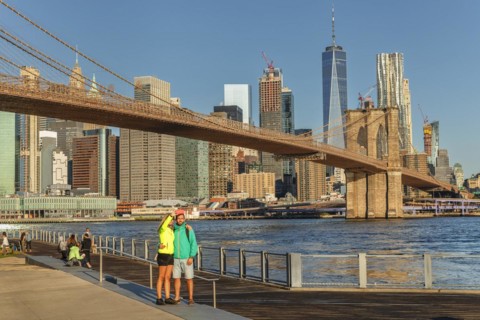 Couple in front of the Manhattan skyline with Brooklyn Bridge and One World Trade Centre, New York