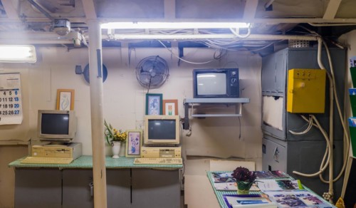 Interior of wardroom with desk chair computer and magazines inside battleship on display at