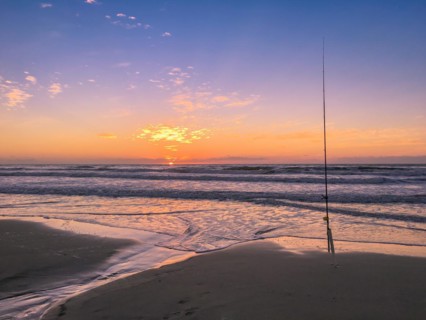 Fishing rod on beach at sunset, surfing cast