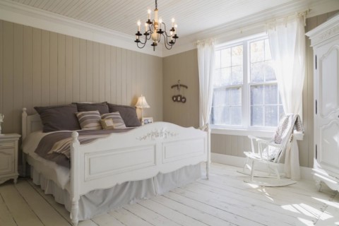 King size bed with light brown and beige striped bedspread, white painted wooden headboard and