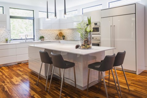 White high-gloss lacquered cabinets and island with grey leather bar stools and white quartz