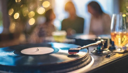 Friends enjoy drinks vinyl record playing together in cozy setting at sunset, bokeh effect ai