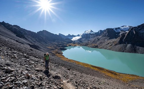 Mountaineers on the way to the Ala Kul Pass, turquoise Ala Kul mountain lake in the morning light,