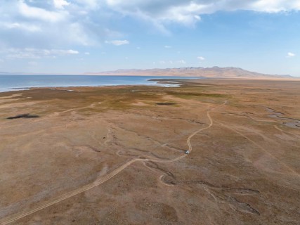 Road and off-road vehicle, Aerial view, Vast empty landscape at the mountain lake Song Kul in