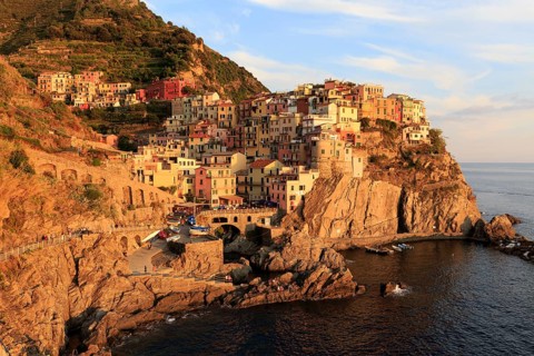 Evening light illuminates Manarola, a picturesque Italian coastal town on cliffs above the sea,