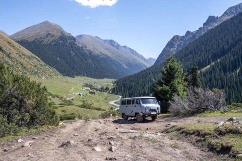 UAZ Buchanka, Russian off-road vehicle on 4x4 track, green mountain valley with village Altyn