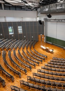 View from above into an empty lecture theatre with rows of seats and lectern, interior photo,