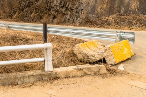 End buttress of street curb broken off and laying on ground at intersection in countryside in South