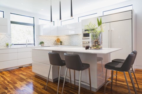 White high-gloss lacquered cabinets and island with grey leather bar stools and white quartz